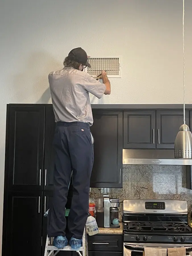 Technician inspecting an air vent during HVAC service in Claremont